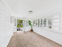Sun-drenched porch featuring all-white decor, carpeted floor, and multiple windows at 907 S A St, Elwood, IN 46036