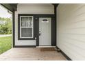 Close-up of a welcoming front porch with a wooden deck, stylish white door, and black trim at 9317 E 36Th Pl, Indianapolis, IN 46235