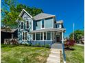 Inviting home exterior featuring a covered front porch, blue siding, and well-manicured landscaping at 1034 N Tacoma Ave, Indianapolis, IN 46201