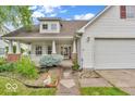 Attractive two-story home featuring a welcoming front porch, two-car garage, and well-maintained landscaping at 10717 Morristown Ct, Carmel, IN 46032