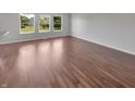 Empty living room featuring hardwood floors, neutral paint, and bright windows with neighborhood views at 11753 Pawleys Ct, Indianapolis, IN 46235
