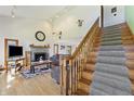 Open-concept living room with vaulted ceilings, a stone fireplace, hardwood floors, and a staircase to the second floor at 11875 W 700 S, Columbus, IN 47201