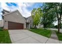 Charming brick home with a manicured lawn, a paved driveway, and established trees in a serene setting at 13271 Aquamarine Dr, Carmel, IN 46033