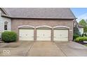 Close up of a three car garage with carriage style doors and mature landscaping at 14711 Macduff Dr, Noblesville, IN 46062