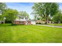 Beautiful two-story home with a well-manicured lawn, mature trees, and a welcoming residential street at 1495 E 240 N, Anderson, IN 46012