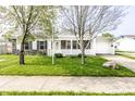 Cozy home with a well-maintained lawn and a front porch, complemented by mature trees and a paved driveway at 315 Schoolhouse Rd, Franklin, IN 46131