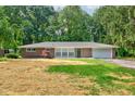 Charming brick ranch home featuring an attached garage and a tree-lined front yard at 3339 Devereaux Dr, Indianapolis, IN 46228
