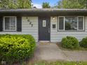 Home featuring a dark front door with sidelight, green bushes, and a 'Welcome' mat at 3627 N Brentwood Ave, Indianapolis, IN 46235