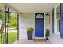 Close-up view of a blue front door with a covered porch, enhanced by plants and black railings at 425 Patterson Rd, Columbus, IN 47203