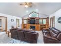 Inviting living room with vaulted ceilings, a fireplace, custom built-ins, and comfortable leather seating at 4399 Summerhaven Dr, New Palestine, IN 46163