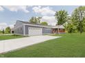Low angle showing this single-story home with a driveway, garage, well-maintained lawn, and covered porch with attractive wooden railings at 4477 Devon Lake Rd, Indianapolis, IN 46226