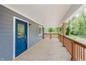 Inviting covered porch features a blue front door, wooden floor, brown posts and railings providing a warm welcome to the home at 4477 Devon Lake Rd, Indianapolis, IN 46226