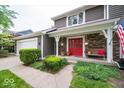Close-up of a home's entry featuring a red door, brick accents, bench, and manicured landscaping at 506 Deerberry Dr, Noblesville, IN 46062