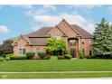 Elegant brick home with a manicured lawn and mature landscaping, showcasing curb appeal at 5251 Apache Moon, Carmel, IN 46033