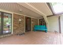Inviting covered porch with brick accents, a charming blue bench, and views of the surrounding landscape at 5821 Bittersweet Rd, Morgantown, IN 46160