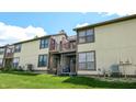 View of the back of the townhome featuring a deck, balcony, and large windows overlooking the grassy lawn at 608 Cielo Vista Dr, Greenwood, IN 46143
