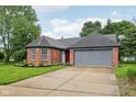 Charming brick home featuring an attached garage and a well-manicured lawn, with a red front door at 7061 Woodgate Cir, Fishers, IN 46038
