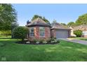 Beautiful brick home with a well-maintained lawn, manicured landscaping, and a gray two-car garage at 7061 Woodgate Cir, Fishers, IN 46038