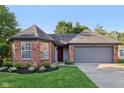 Charming brick home featuring an attached garage and a well-manicured lawn, with a red front door at 7061 Woodgate Cir, Fishers, IN 46038