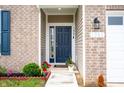 Close-up of a home's blue front door with decorative plants and visible house number on a brick facade at 1065 Bent Branch Ln, Greenwood, IN 46143
