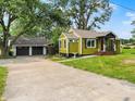 Green home with a detached two-car garage and a concrete driveway in a lush, grassy setting at 10854 E 700 N, Wilkinson, IN 46186