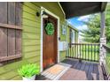 Inviting front porch featuring a wooden door with wreath and a welcome mat, set against green siding at 10854 E 700 N, Wilkinson, IN 46186