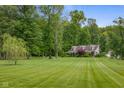Home exterior featuring a lush green lawn, mature trees, and well-maintained landscaping at 12383 S 25 W, Columbus, IN 47201