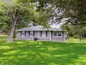 Single story home with gray siding, lush green yard, white picket fence and mature trees at 12508 N Jackley Rd, Elwood, IN 46036