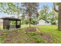 Backyard featuring a cozy gazebo, lush trees, and green grass surrounding the home at 233 N Devon Ave, Indianapolis, IN 46219