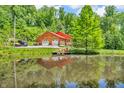 Scenic view of a log home with a red metal roof, complemented by a serene pond and dock at 2780 W Grizzly Trl, Martinsville, IN 46151