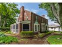 An elegant brick house featuring a screened porch and lush backyard garden at 5165 E Pleasant Run Pkwy S Dr, Indianapolis, IN 46219