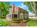 Beautiful brick home featuring a screened porch, mature landscaping, and a classic architectural style at 5165 E Pleasant Run Pkwy S Dr, Indianapolis, IN 46219