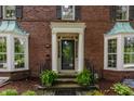 The front entrance with a black door is flanked by bay windows and ferns at 5165 E Pleasant Run Pkwy S Dr, Indianapolis, IN 46219
