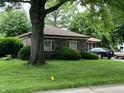 Well-maintained brick home featuring a lush, green lawn and mature trees providing ample shade at 539 Queenswood Dr, Indianapolis, IN 46217