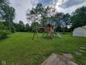 Large backyard featuring a wooden playset, green lawn, and storage shed at 5515 Lunsford Dr, Indianapolis, IN 46237
