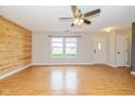 Bright living room with wood-look floors, a modern ceiling fan, and a view of the front yard through large windows at 560 Tracy Ln, Brownsburg, IN 46112