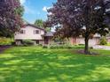 Beautiful two-story home with well-manicured lawn, mature trees, and classic architectural details on a sunny day at 5730 Teresa Dr, Alexandria, IN 46001