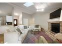 Bright living room featuring a brick fireplace, skylight, and comfortable seating at 5873 N Victoria Dr, Indianapolis, IN 46228