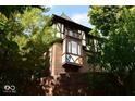 Charming turret detail with brick facade, decorative emblems, and Tudor accents, surrounded by mature trees at 6412 Fall Creek Rd, Indianapolis, IN 46220