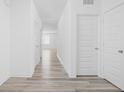 Bright hallway featuring wood-look floors, white walls, and multiple doors leading to various rooms at 7431 Stillness Dr, Indianapolis, IN 46268