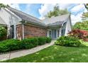 View of the home's entrance with brick accents, landscaping, and a walkway leading to the front door at 8713 Champions Dr, Indianapolis, IN 46256
