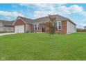 Well maintained brick home featuring a manicured lawn, landscaping and a two car garage at 107 Elliott Ave, Trafalgar, IN 46181