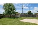 Large backyard with a grassy lawn, wooden fence, storage shed, and concrete patio area at 1129 Central Park S Blvd, Greenwood, IN 46143