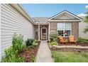 Inviting front porch with brick accents, complemented by colorful flowers and stylish outdoor seating at 12496 Wolf Run Rd, Noblesville, IN 46060