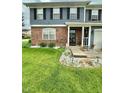 Close up of well maintained front lawn with flower bed and partial brick facade on home at 1831 Beckenbauer Ln, Indianapolis, IN 46214