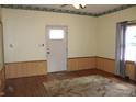 Living room featuring hardwood floors, wood paneled walls, a window, and a door to the exterior at 202 S Church St, Brooklyn, IN 46111