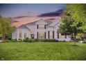 Two-story white brick home at sunset with lush lawn, manicured landscaping, and beautiful curb appeal at 2535 Dawn Ridge Dr, Westfield, IN 46074