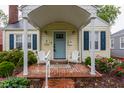 Charming house featuring brick porch with Adirondack chairs, a light blue front door, and manicured landscaping at 28 N Elizabeth St, Indianapolis, IN 46219