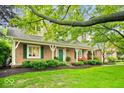 Charming brick home featuring a covered porch with stylish red chairs and lush landscaping at 3295 Allison Ct, Carmel, IN 46033