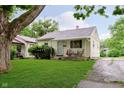 Inviting single-story home with a green lawn, mature trees, and covered front porch at 3338 Orchard Ave, Indianapolis, IN 46218